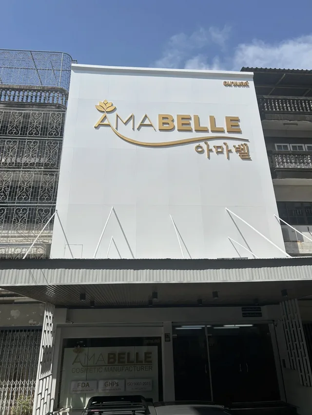ป้ายตัวอักษรโลหะสีทอง AMABELLE ติดตั้งบนแผงฟาซาดสีขาวของอาคารบริษัท