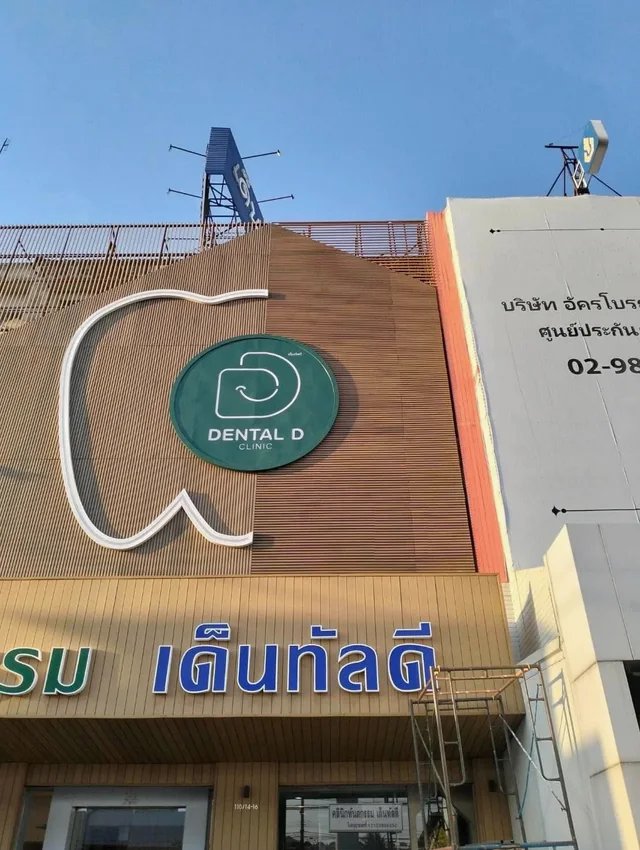 ฟาซาดคลินิก Dental D Clinic ผนังระแนงลายไม้พร้อมป้ายโลโก้รูปฟันและตัวอักษรหน้าร้าน