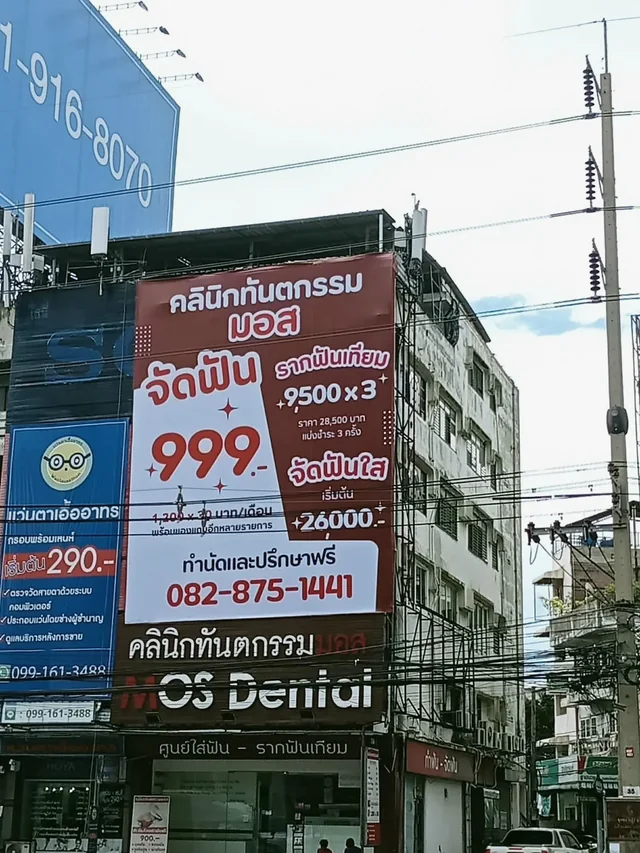 ป้ายโฆษณาขนาดใหญ่คลินิกทันตกรรมมอสบนอาคารพาณิชย์ พร้อมโปรโมชั่นจัดฟันและป้ายหน้าคลินิก